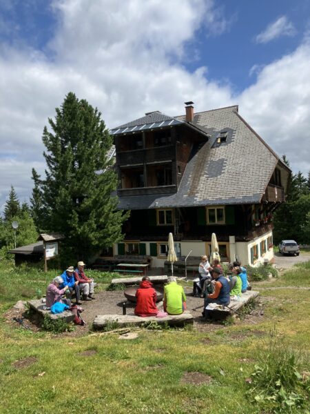 A group of people sitting around a fire pit in front of a large house.